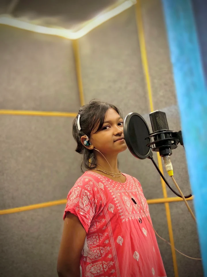 Young singer with an in-ear monitor at the studio microphone